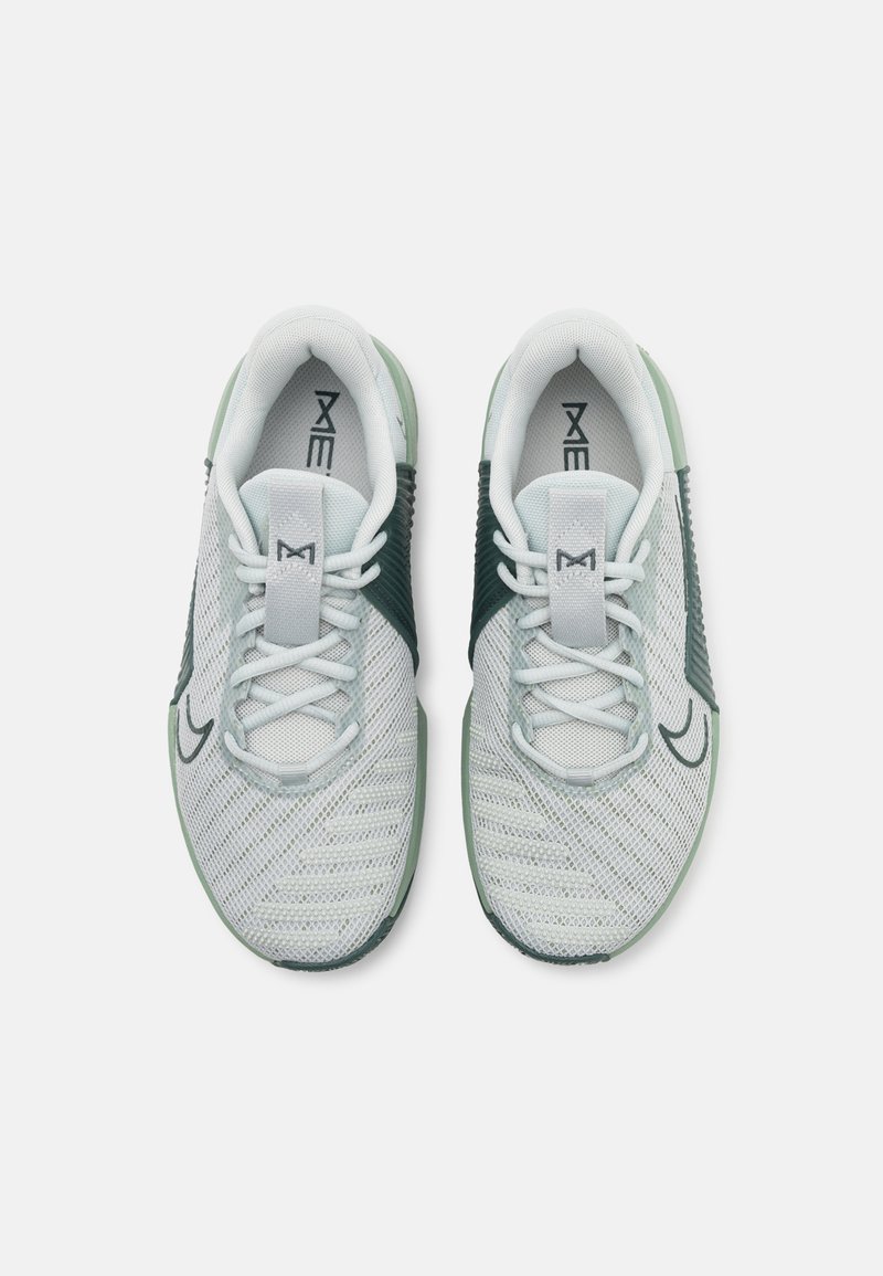 Zapatillas deportivas de color gris claro con parte superior de malla, acentos verdes y cordones. Presentan una punta redonda y paneles laterales texturizados para ventilación.