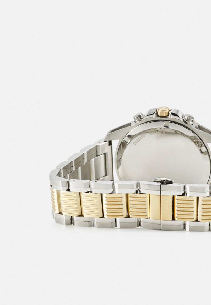 Montre-bracelet en acier inoxydable avec un bracelet bicolore ; accents argent et or avec un motif texturé ; boîtier rond et couronne proéminente.