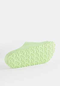 Chaussure d'été verte claire à enfiler avec une semelle en caoutchouc texturée à motif hexagonal. Design supérieur lisse, bout arrondi et sans fermetures visibles.