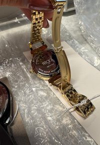 Goldene Armbanduhr mit Edelstahlarmband, rundem Zifferblatt und transparentem Rückenteil, das die Marke "regal" sowie Angaben zur Wasserfestigkeit zeigt.