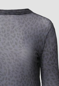 Doorzichtig langarmtop, grijs met een luipaardpatroon. Lichte stof met een gladde textuur en een ronde halslijn. Zachte afwerking.