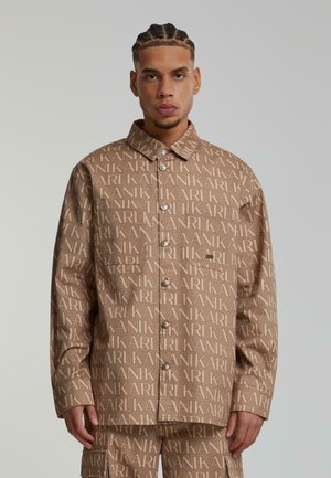 Braune Hemdjacke mit einem durchgehenden, wiederholten "KARL"-Logo-Muster, Knopfverschluss und einem klassischen Kragen-Design. Glatte Textur und lässige Passform.