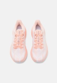 Light pink athletic shoes with a mesh upper, textured patterns, rounded toe, and flat laces. Features a cushioned sole for comfort.