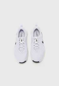 Bílé atletické tenisky s síťovinovým svrškem, černými akcenty po stranách a polstrovanou podrážkou. Šňůrky a poutko v kontrastní barvě.