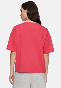 Kortærmet t-shirt i lys pink i 100% bomuld med en afslappet pasform, rund halsudskæring og synlige sømdetaljer. Bæres med grå shorts.