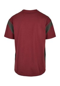 Camiseta de manga corta con cuerpo color granate y paneles laterales verde oscuro, confeccionada en algodón suave, con cuello redondo y bajo recto.