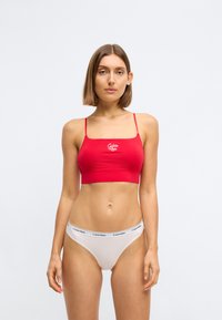 Rode rekbare bralette met dunne bandjes, voorzien van een wit logo. Gecombineerd met een lichtgrijze tanga met een zwarte logo-elastiek.