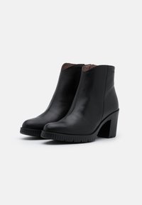 Schwarze Lederstiefeletten mit einer glatten Oberfläche, hohem Blockabsatz und gerippter Sohle. Schlankes, stromlinienförmiges Design mit minimalistischer Ästhetik.