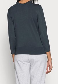 Dark teal sweater with a round neckline, three-quarter sleeves, and ribbed trim; smooth texture, fitted design, simple and minimal style.