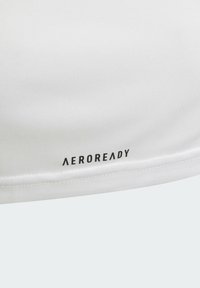 Haut de sport blanc avec le logo AEROREADY. Tissu lisse et léger avec un design épuré et des coutures visibles le long de l'ourlet.
