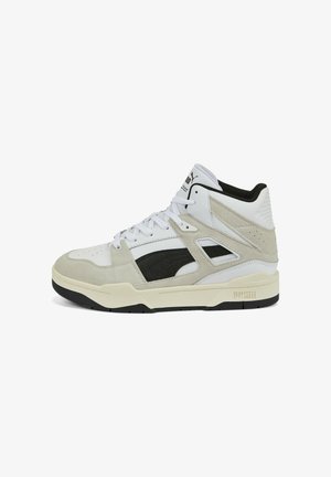 Baskets montantes Puma blanches et beiges avec des accents noirs, bout perforé et semelle épaisse crème, vues du côté gauche.