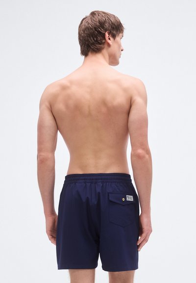 Marineblå badebukser med elastisk midje, baklomme, og lett, glatt stoff. Enkelt design uten mønstre.