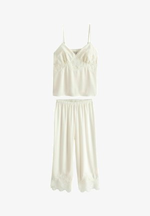 Krémová dvojdielna súprava nočného prádla, ktorá obsahuje tílko s čipkovým lemom a pyžamové nohavice s vlnitým čipkovým okrajom. Hladká textúra látky.