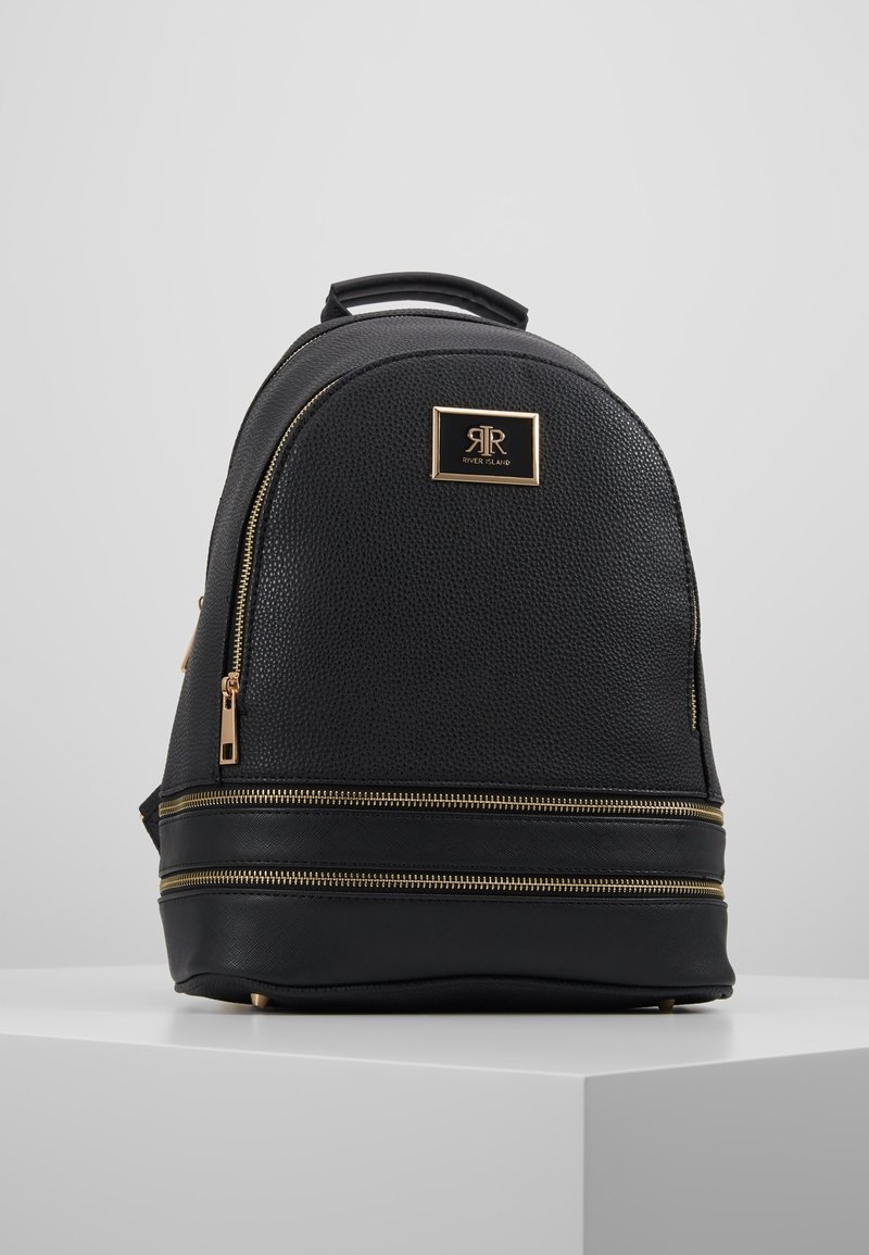 Czarny plecak o fakturze przypominającej kamyki, zaokrąglony kształt, złote akcenty metalowe, podwójne zamki błyskawiczne oraz płytka z logo z przodu.