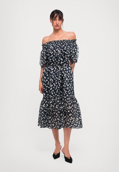 Strapless marineblaues Kleid mit weißem Blumendruck, transparentem Stoff, Puffärmeln und gestuftem Rüschensaum; kombiniert mit schwarzen Spitzeriehelsen.