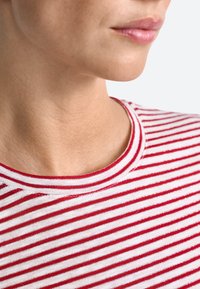 Crvena i bijela prugasta majica kratkih rukava s okruglim izrezom, koja ima mekanu teksturu i uske horizontalne linije.