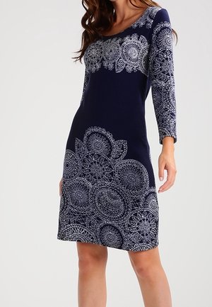 Robe marine à manches trois-quarts, ornée de motifs en dentelle blanche compliqués au niveau du corsage et de l'ourlet. Fabriquée dans un tissu doux avec un design ajusté.
