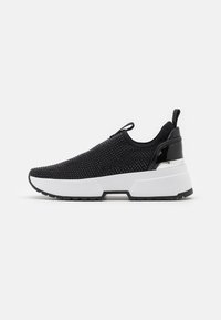 Černé slip-on tenisky s texturovaným síťovaným svrškem, bílou chunky podrážkou, lesklými černými akcenty a poutkem na patě.