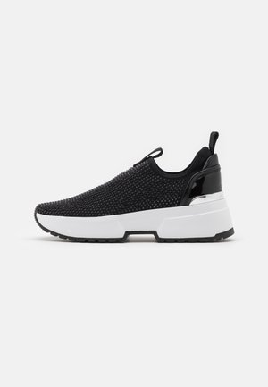 Baskets noires à enfiler avec une tige en maille texturée, semelle épaisse blanche, accents noirs brillants et tirant au talon.