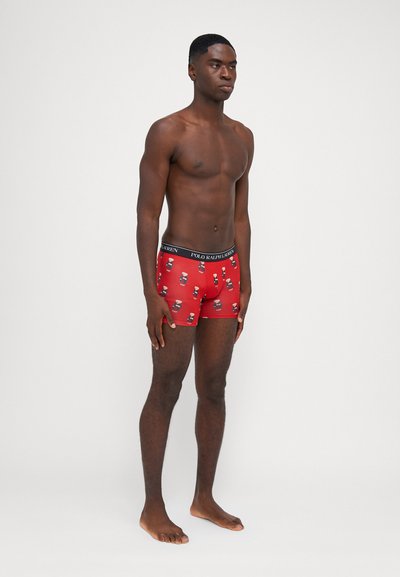 Boxer rouge avec une ceinture élastique noire portant le texte "POLO RALPH LAUREN" ; orné d'un motif de ours en cartoon répété.