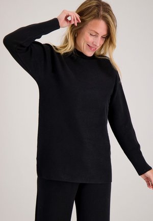 Zwarte pullover trui met een hoge hals, gemaakt van zacht stof. Heeft lange mouwen met geribbelde manchetten en een relaxte pasvorm.