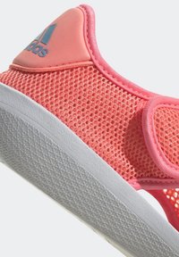 Scarpa slip-on rosa in mesh con suola bianca testurizzata, dotata di un colletto imbottito morbido e accento del logo blu sul tallone.
