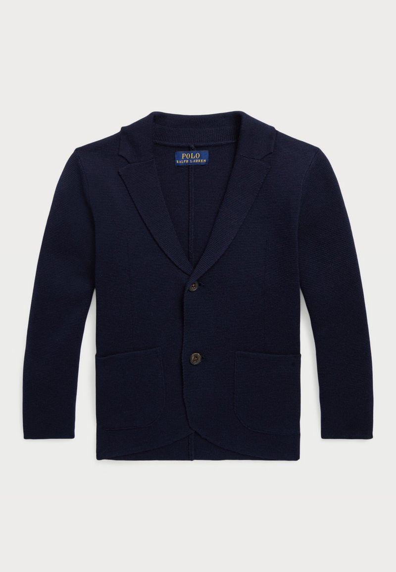 Ναυτικό μπλε πλεκτό καστόρι με γωνιακά πέτα, μπροστινό κλείσιμο με κουμπί και δύο πλαϊνές τσέπες. Ριχτό texture σε όλη την επιφάνεια.