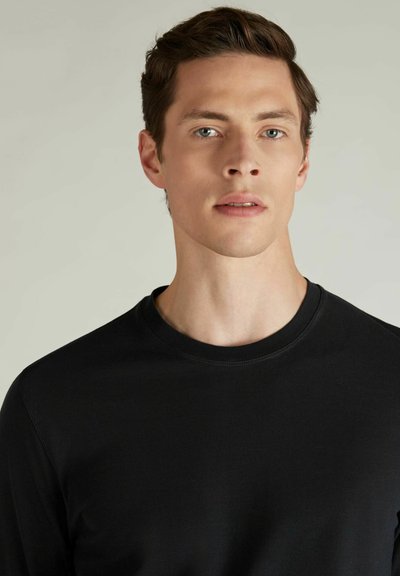 Schwarzes Langarmshirt aus weichem Stoff mit Rundhalsausschnitt und minimalen Nähten. Einfaches Design und figurbetonter Schnitt.