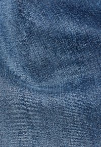 Tessuto denim di un blu profondo, caratterizzato da una consistenza liscia con una leggera lucentezza, che mette in mostra un sottile motivo a tessitura e tonalità variabili.