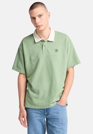 Polo-shirt i lys grøn med en kontrasterende hvid krave. Har korte ærmer, et logo på brystet og en afslappet pasform.