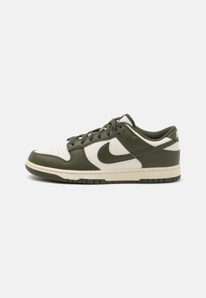 Nike Dunk Sneakers in Weiß und Dunkelgrün, aus Leder im Low-Top-Design mit dem Nike Swoosh an der Seite, weißer Zwischensohle und dunkelgrüner Außensohle.