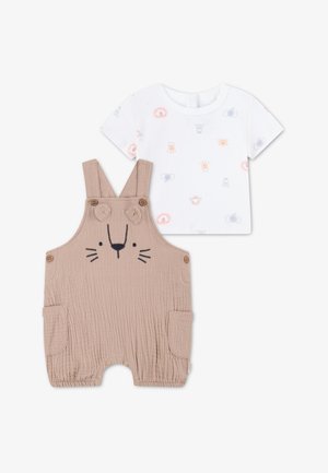 Lyse beige bomullsoveraller med løveansiktbroderi, med knappestropper og sidelommer. Følges av en hvit kortermet skjorte med fargerike dyretrykk.