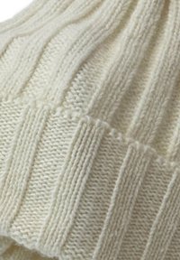 Cream-colored knitted beanie featuring a ribbed texture and alternating patterns, with a soft, stretchy fabric for comfort.