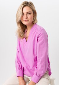 Langdurige mouw, roze blouse met een V-hals, gathered details op de schouders en licht opgeblazen mouwen, gemaakt van een gladde stof.