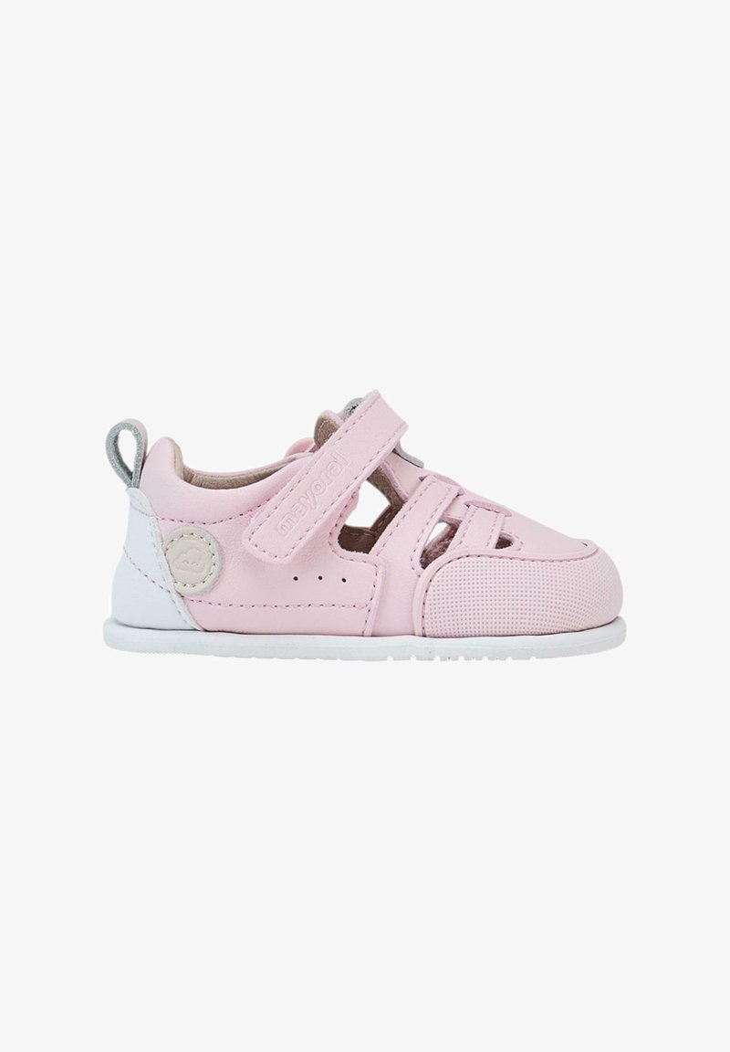 Zapatos infantiles de cuero rosa con diseño perforado, correa ajustable, suela blanca y logotipo de marca. Presentan un acabado texturizado y acentos.