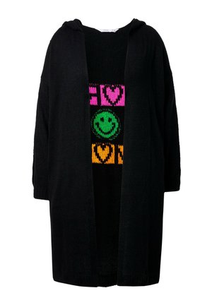 Cardigan noir à capuche avec un devant ouvert et des manches surdimensionnées, porté par-dessus un pull noir à motifs avec des graphiques vifs et colorés.