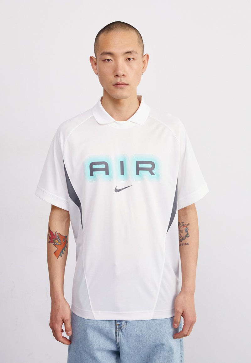 Biela polokošeľa s krátkym rukávom s nápisom "AIR" v tónovanej modrej farbe a logom Nike. Má šedé akcenty po stranách. Mäkký, športový materiál.
