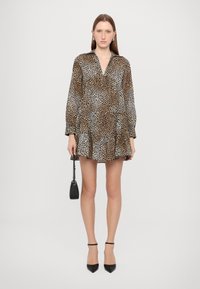 Haljina s leopard uzorkom dugih rukava, koja ima ovratnik i volanasti rub. Dodatci uključuju malu crnu torbicu i crne cipele s visokom petom.