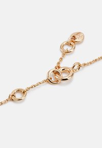 Pulsera de metal tono dorado con acentos circulares interconectados y un cierre de langosta seguro, con un diseño de cadena delicada y superficie lisa.