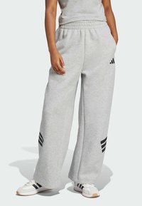 Szare dresy z szerokimi nogawkami, z czarnymi akcentami w postaci trzech pasków po bokach oraz elastycznym pasem dla wygody.