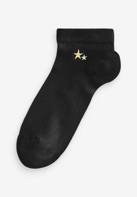 Schwarze Calcetinen aus glattem Stoff. Sie besitzen zwei gestickte Sterne: einen goldenen und einen weißen, die sich nahe dem Bündchen befinden.