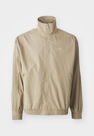 Beige windbreaker jacket with a high collar, elastic cuffs, and waistband. Features zippered front and striped accents along sleeves.