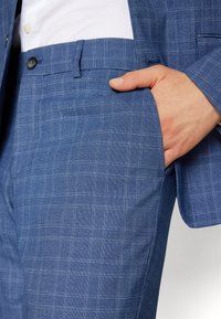 Modré kockované nohavice z kvalitného materiálu, s hladkým povrchom, bočnou kapsou a elegantným dizajnom, doplnené tmavými gombíkmi.