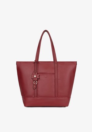 Sac cabas en cuir rouge avec double poignée, poche avant, et breloque attachée en forme de fleur avec détail en anneau.