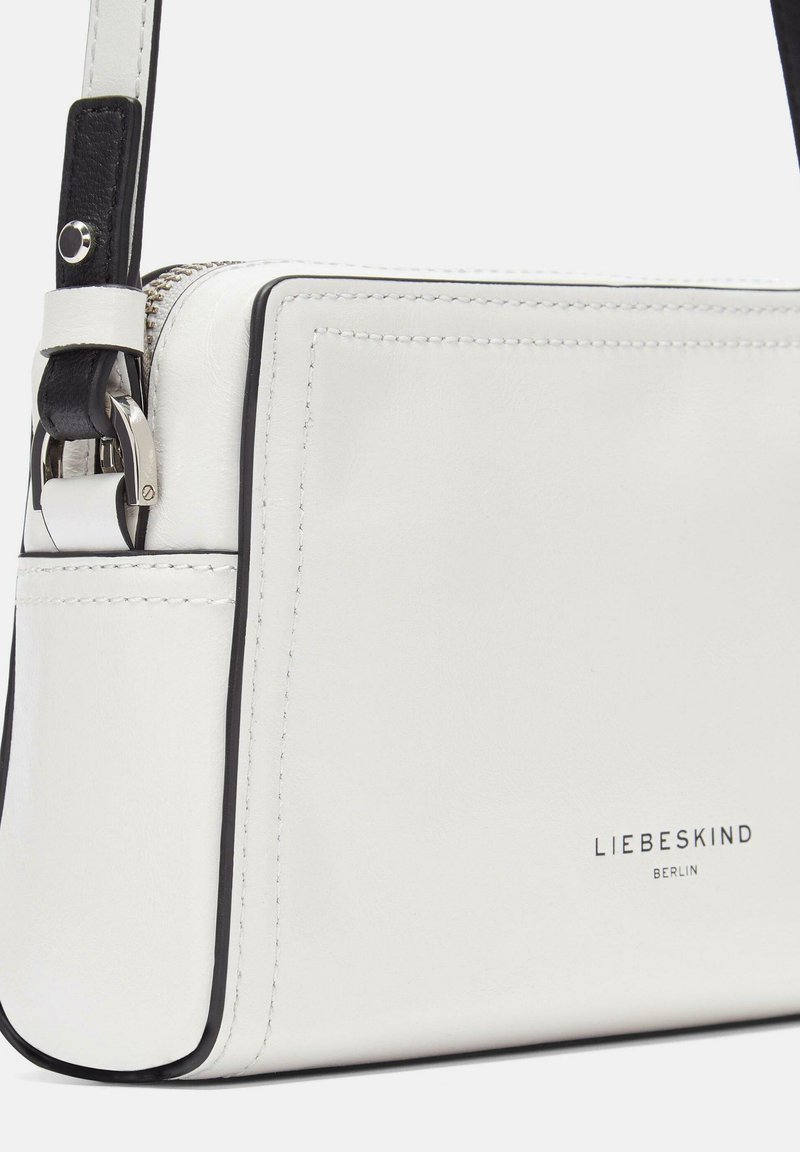 Witte leren crossbody tas met zwarte accenten, rechthoekige vorm, gladde textuur, ritssluiting en ingebracht merklogo.