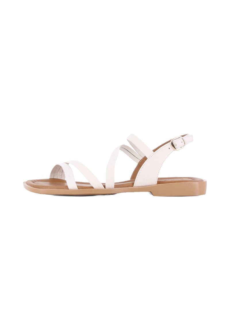 Sandalias blancas con tiras y suela plana, con acentos marrones, que cuentan con una correa de tobillo ajustable y una textura suave.