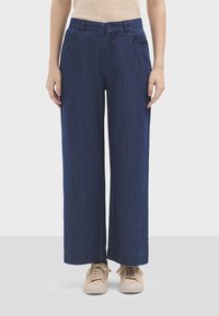 Pantaloni in denim a gamba larga di colore blu scuro, con chiusura a bottone, due tasche frontali e una texture liscia. Rifiniti con orli cuciti.