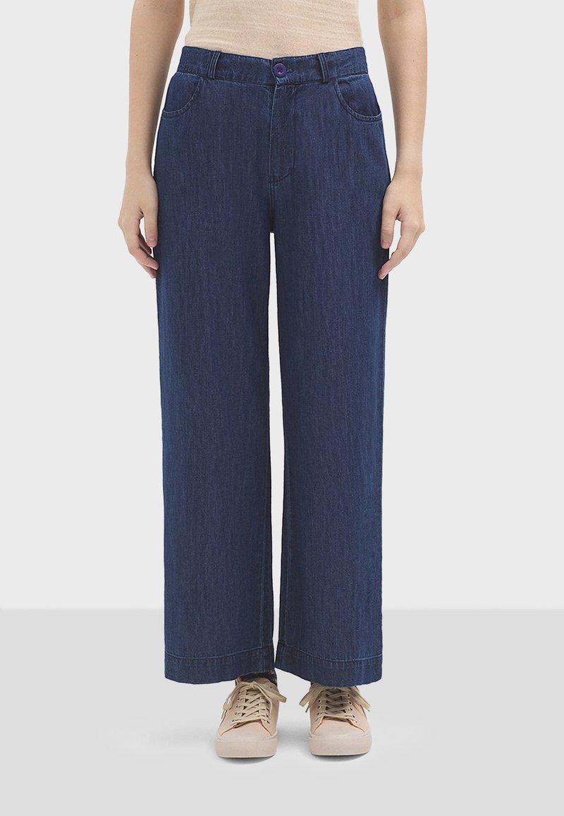 Pantaloni in denim a gamba larga di colore blu scuro, con chiusura a bottone, due tasche frontali e una texture liscia. Rifiniti con orli cuciti.