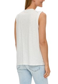 Sleeveless, white top made from lightweight fabric with a round neckline. Features subtle side slits and a relaxed fit.
