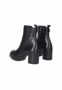 Stivali alla caviglia neri in pelle con tacco spesso, pannelli laterali elasticizzati e zip sul retro. Texture liscia, punta arrotondata e accenti minimali.